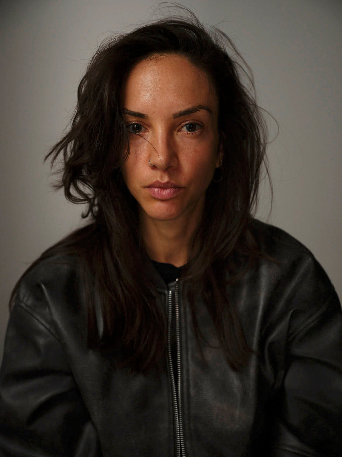 Person wearing a black leather jacket against a plain background