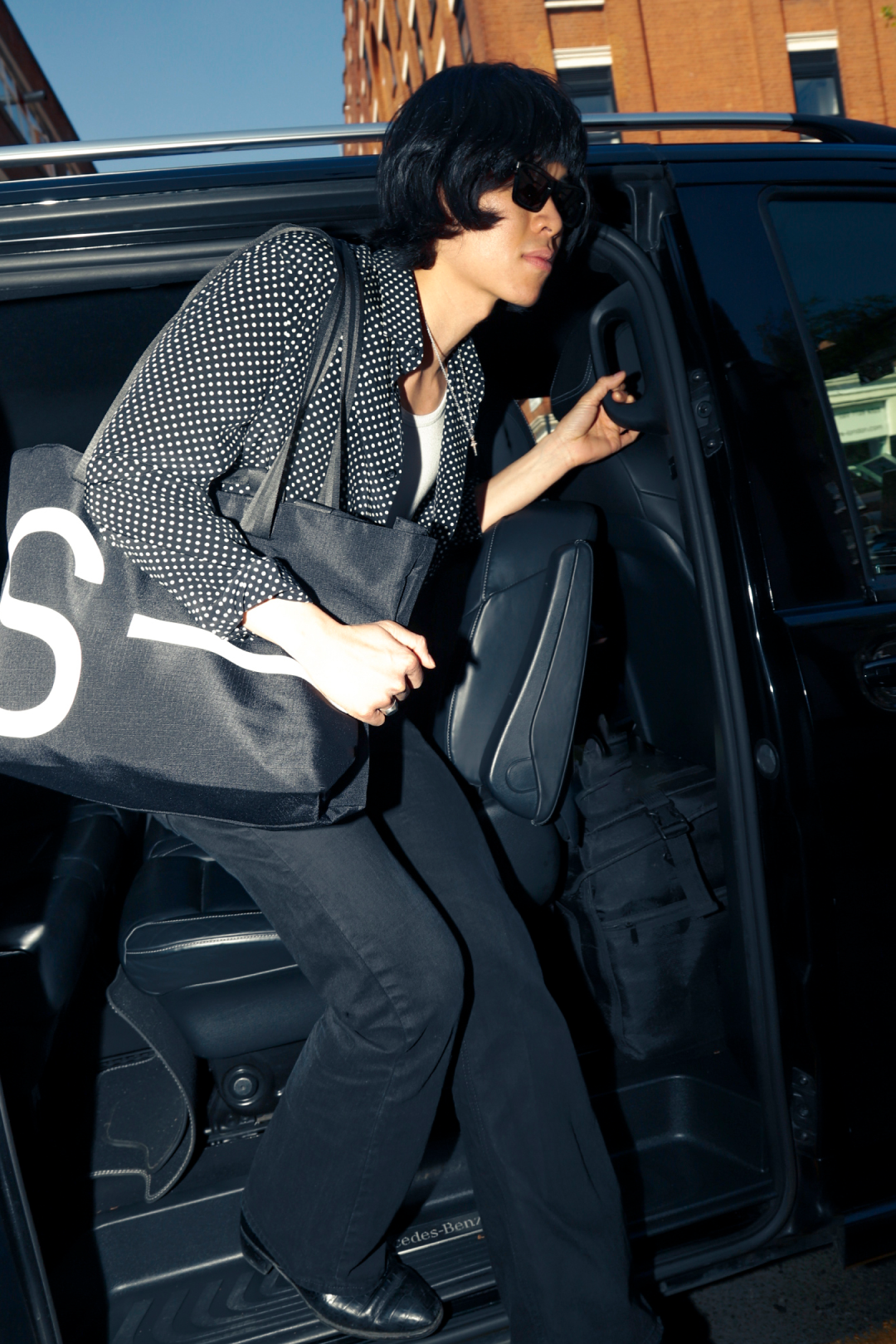 Person getting into a car with a large bag, urban setting