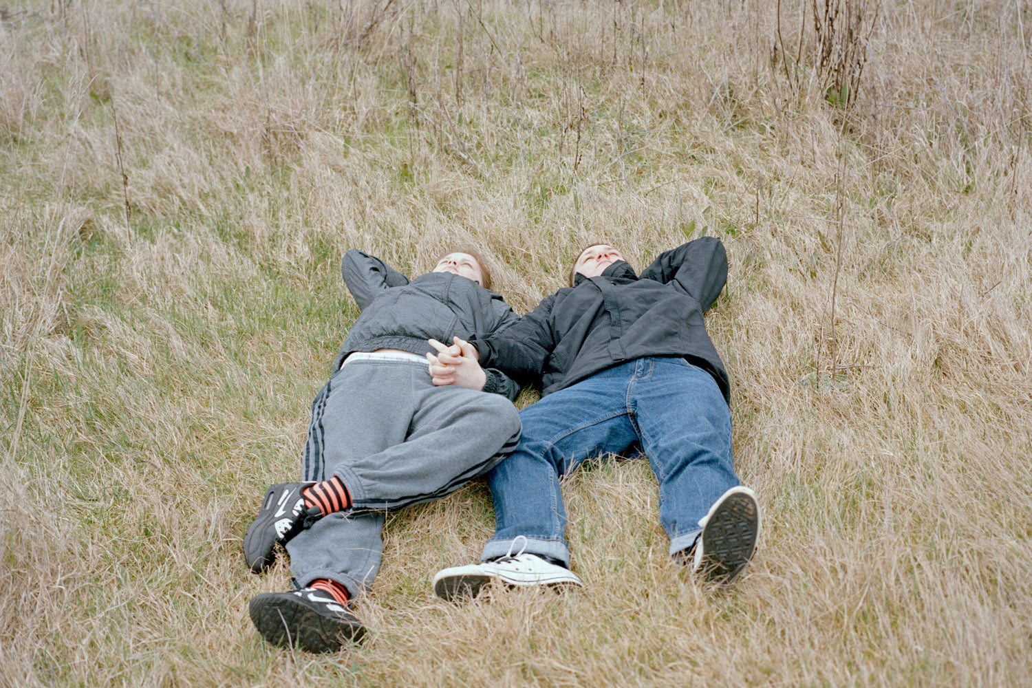 Two people lying on a grassy field wearing matching outfits.